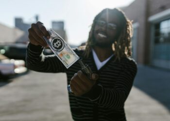 A smiling man in a suit holding a large check labeled $5.4 million with a blockchain symbol.