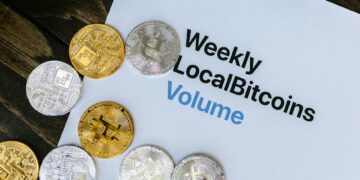 A close-up of Bitcoin tokens stacked on financial documents and a calculator.