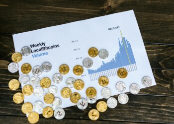 Bitcoin logo surrounded by fluctuating graphs and symbols of DeFi and NFTs.
