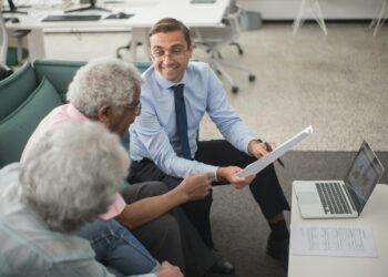 A financial advisor discusses cryptocurrency investment options with clients at a Schwab office.