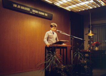 Sam Altman speaking at a podium, addressing the Tumbler Ridge shooting incident.
