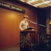 Sam Altman speaking at a podium, addressing the Tumbler Ridge shooting incident.