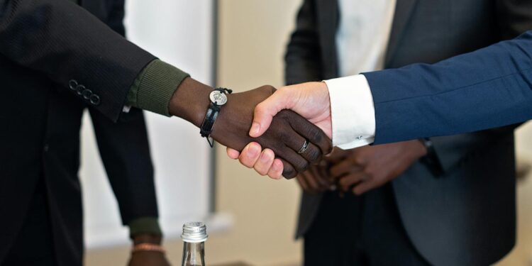 Coreweave and Anthropic executives shaking hands in an office setting, symbolizing partnership.