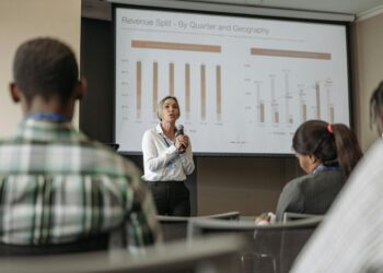 Stephanie Cutter speaking at a conference with financial graphs displayed in the background.
