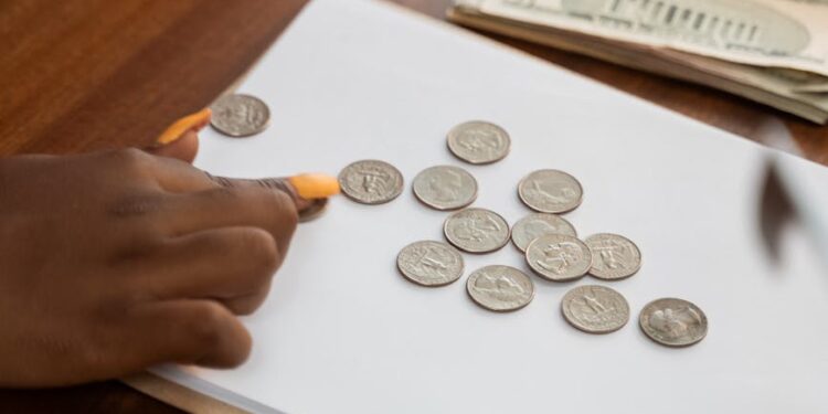 Hands counting cryptocurrency coins with a financial document and calculator in the background.