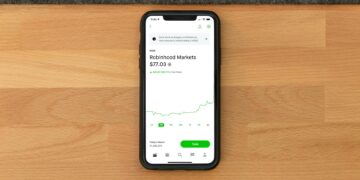 A smartphone displaying Robinhood and OpenAI logos with financial charts in the background.