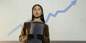 Cambodian senator Kok An speaking at a government event, with financial charts in the background.