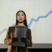Cambodian senator Kok An speaking at a government event, with financial charts in the background.