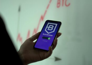 Revolut logo on a smartphone screen with financial graphs and crypto symbols in the background.