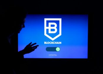 A researcher stands before a digital screen displaying Bitcoin and quantum computing graphics.
