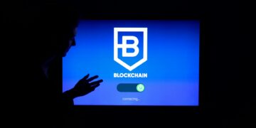 A researcher stands before a digital screen displaying Bitcoin and quantum computing graphics.