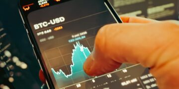 A man checks cryptocurrency prices on a smartphone amidst financial news articles.