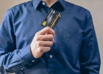 A person holding a debit card labeled "MoonAgents" with cryptocurrency symbols in the background.