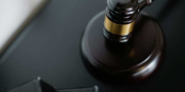 A gavel rests on financial documents, symbolizing legal settlement in crypto fraud case.