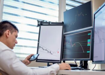 Traders analyzing stock charts with digital screens showcasing tokenized stocks and ETFs.