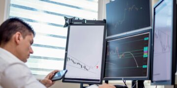 Traders analyzing stock charts with digital screens showcasing tokenized stocks and ETFs.