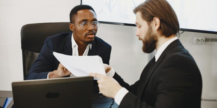 Two professionals discussing crypto payment solutions at a conference table with charts and laptops.