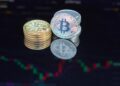Bitcoin coins stacked with financial charts and graphs in the background, symbolizing investment.