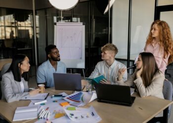 A group of diverse professionals discusses regulations on prediction markets in a conference room.