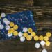 Crypto coins scattered with a backdrop of financial charts and sanctions symbols.