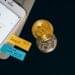 A person checks cryptocurrency charts on a smartphone amid financial news headlines.